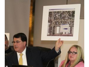 Supervisor Shawn Nelson holds up an aerial view of the site for a proposed homeless shelter during a public meeting at the Fullerton Library in March.